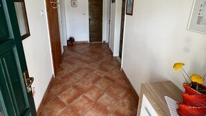 A hallway with tiled flooring, a wooden door, and a wall-mounted air conditioning unit. - Apartments Luna (Marina)