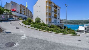 En byggnad med flera våningar, balkonger, en parkeringsplats och utsikt över havet.