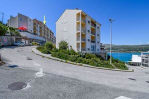 Ein mehrstöckiges Gebäude mit Balkonen, einem Parkplatz und Meerblick.