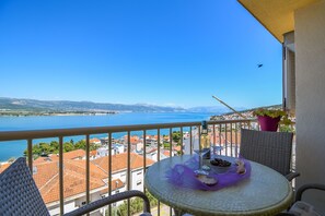 A balcony with a table, a chair, and a potted plant. - Apartment Dani (Trogir)