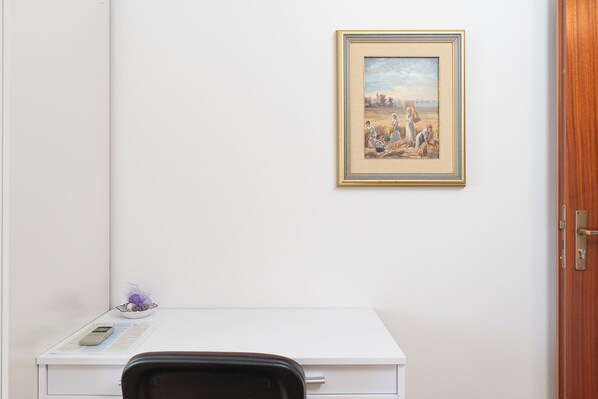 A room with a white desk, a framed painting, and a wooden door. - Apartment Porat (Starigrad)