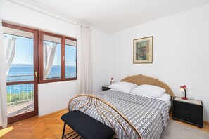 Une chambre à coucher avec un lit, un banc, une table de chevet, une lampe et un tableau.