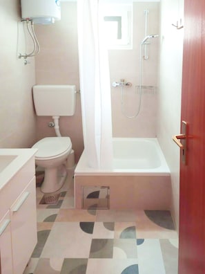 Een compacte badkamer met een toilet, douche en bad.