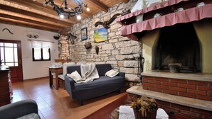 Ein gemütliches Wohnzimmer mit Steinwand, Kamin, einer Couch und einem Essbereich.