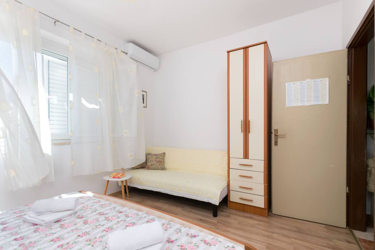 Une chambre à coucher comprenant un lit, une petite table, un canapé, une armoire et une porte sur laquelle est affiché un avis.