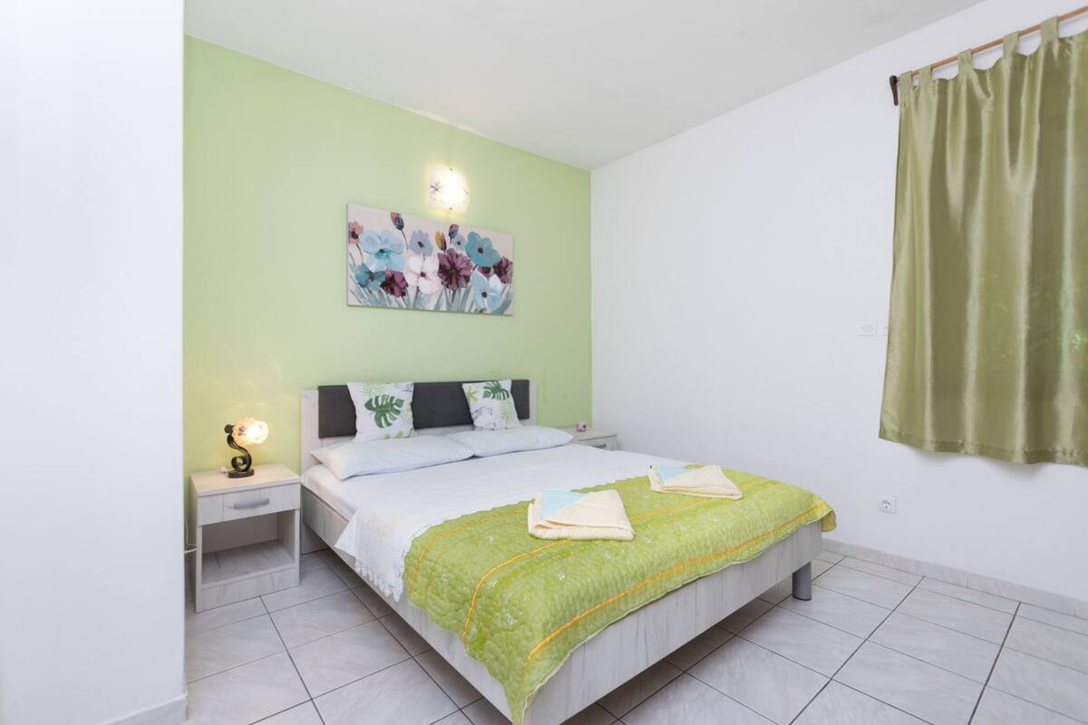 Une chambre à coucher avec un lit, une table de chevet et un tableau accroché au mur.