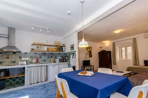 A compact kitchen with a dining area, a TV, and a bed. - Apartment City Center (Jelsa)