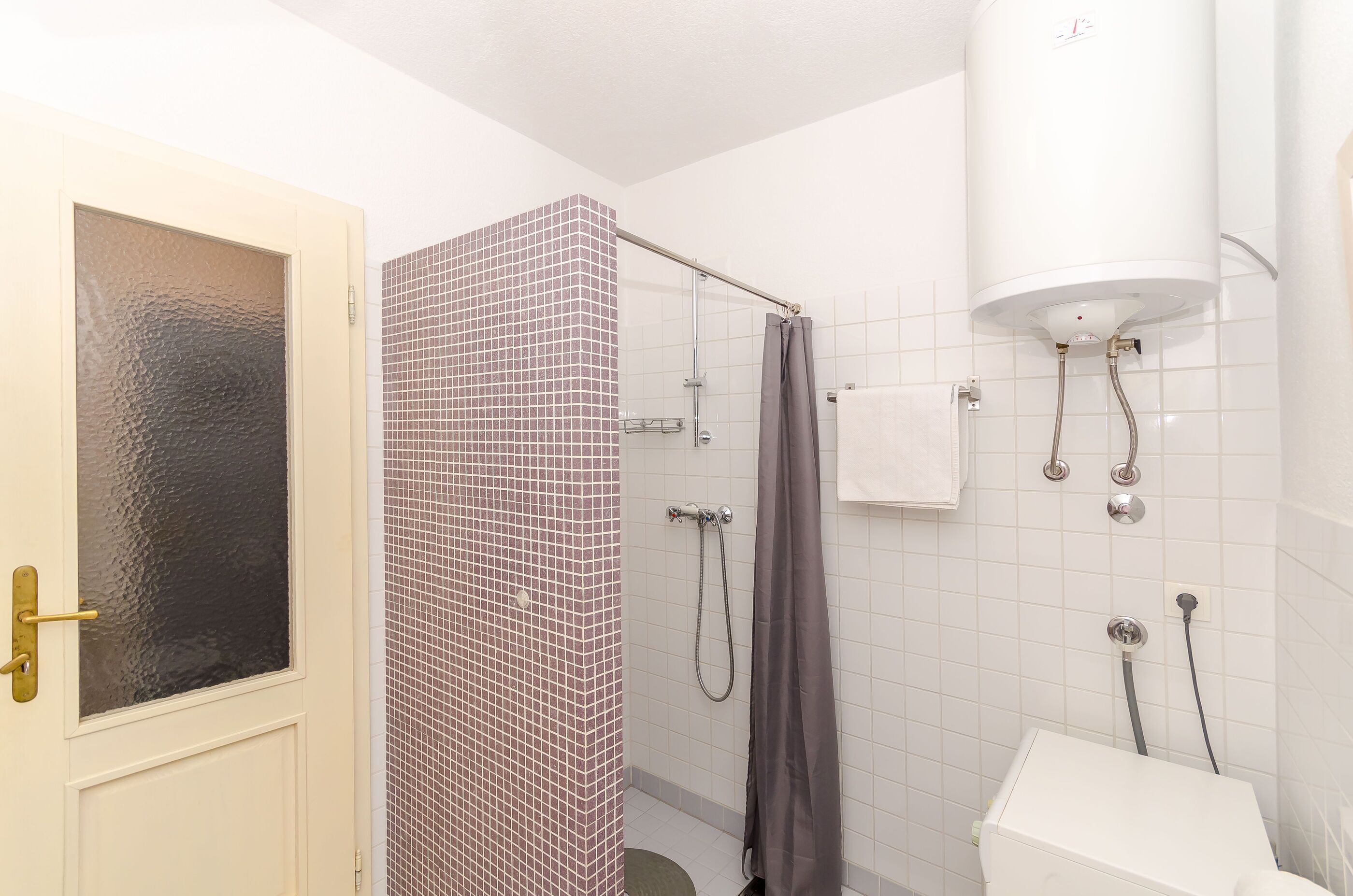 A bathroom with a shower, a toilet, and a towel rack.