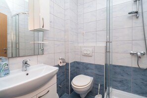 Une salle de bain moderne avec une douche à parois de verre, un lavabo blanc et des toilettes.