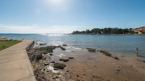 A concrete pathway along a water body with a clear sky. - Apartment Terezija by the sea (Privlaka)