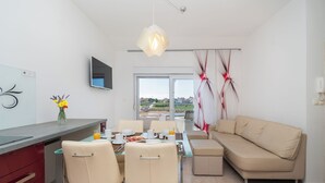 A modern dining area with a glass table, beige chairs, and a sofa. - Apartment Terezija by the sea (Privlaka)