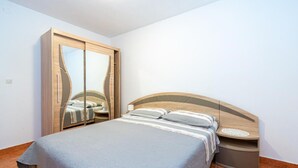 Een slaapkamer met een bed, een houten garderobe en een nachtkastje.