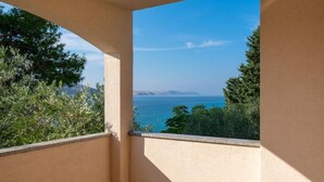 Een balkon met uitzicht op zee en verre bergen.