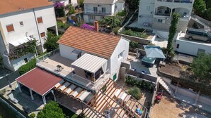 A residential area with multiple houses, including a two-story building with a balcony and a covered patio area. - Apartment Adria (Trogir)
