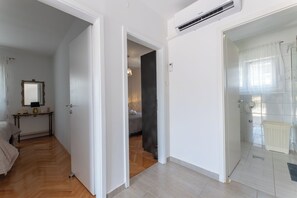 A hotel room with a wooden floor, a bed, a bedside table with a lamp, and a mirror on the wall. - Apartment Adria (Trogir)