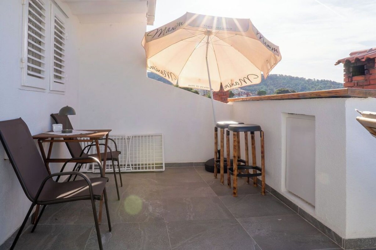 Eine Terrasse mit Tisch, Stühlen, Sonnenschirm und einer Bar.