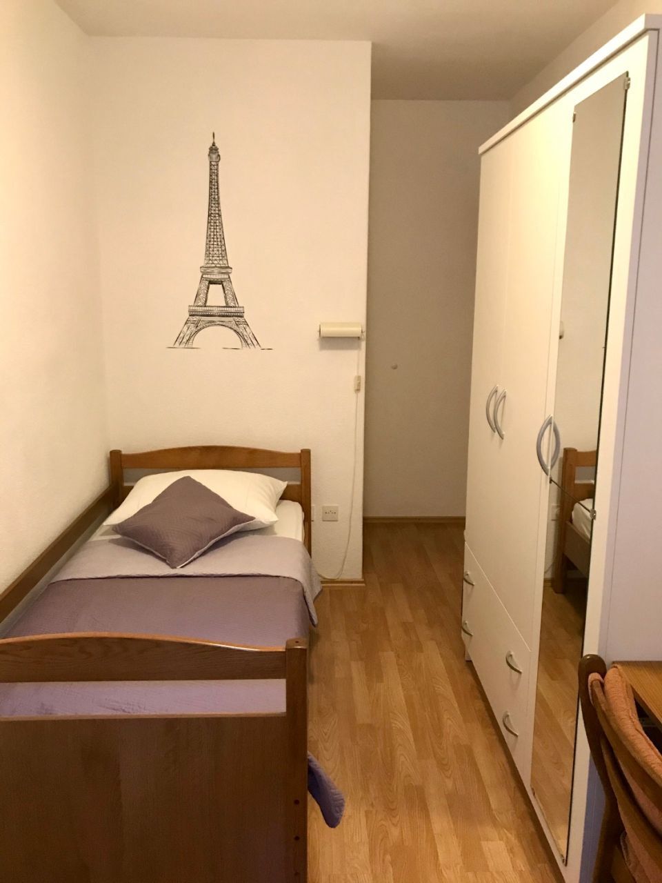 A bedroom with a bed, a wardrobe, and a mirror.