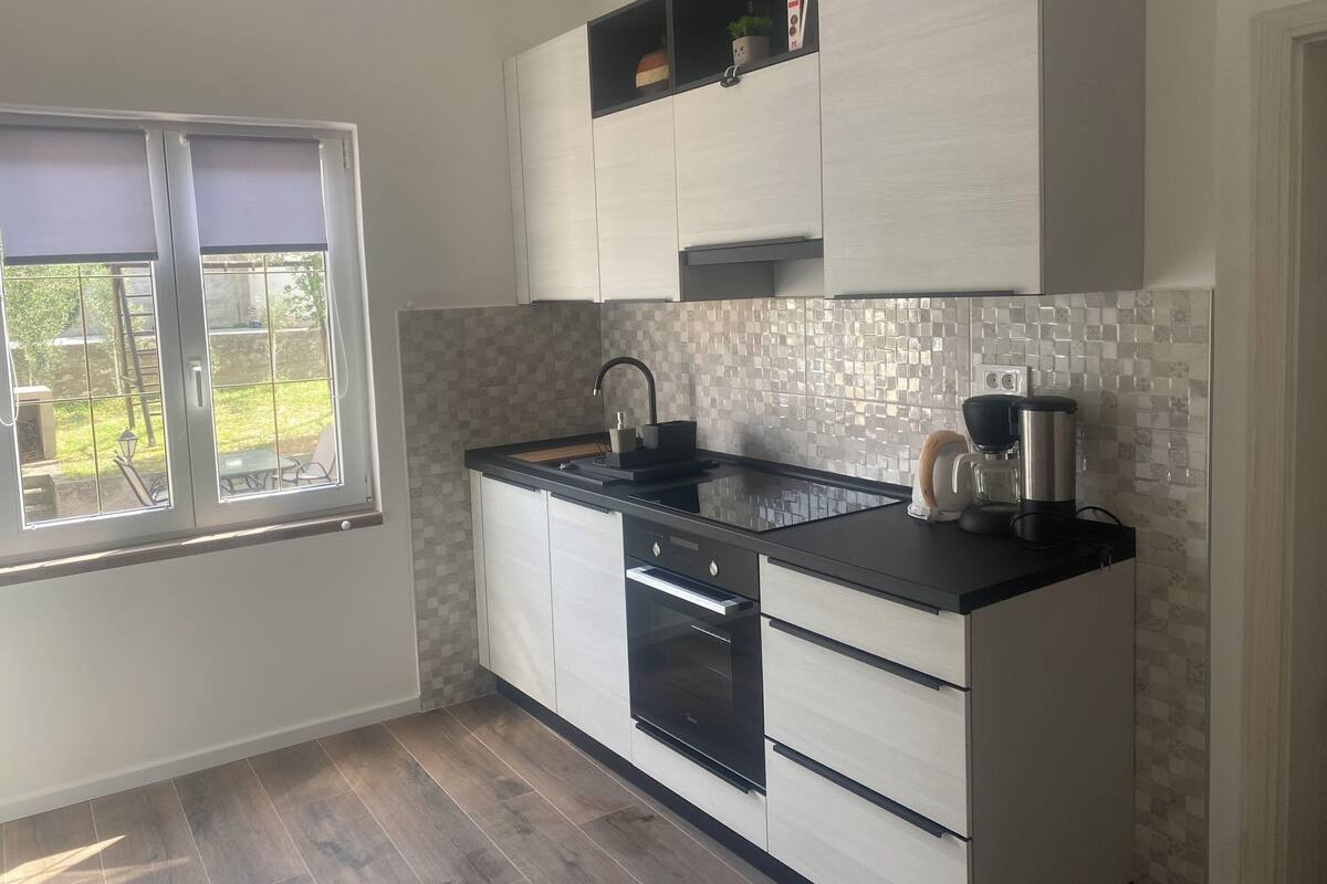 A modern kitchen with white cabinets, a black countertop, and a tiled backsplash.