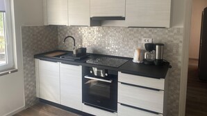 A modern kitchen with a black countertop, stainless steel appliances, and a tiled backsplash. - Apartments Paradise (Lopar)