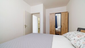 A bedroom with a bed, a wooden wardrobe, and a door leading to a bathroom. - Apartments Paradise (Lopar)