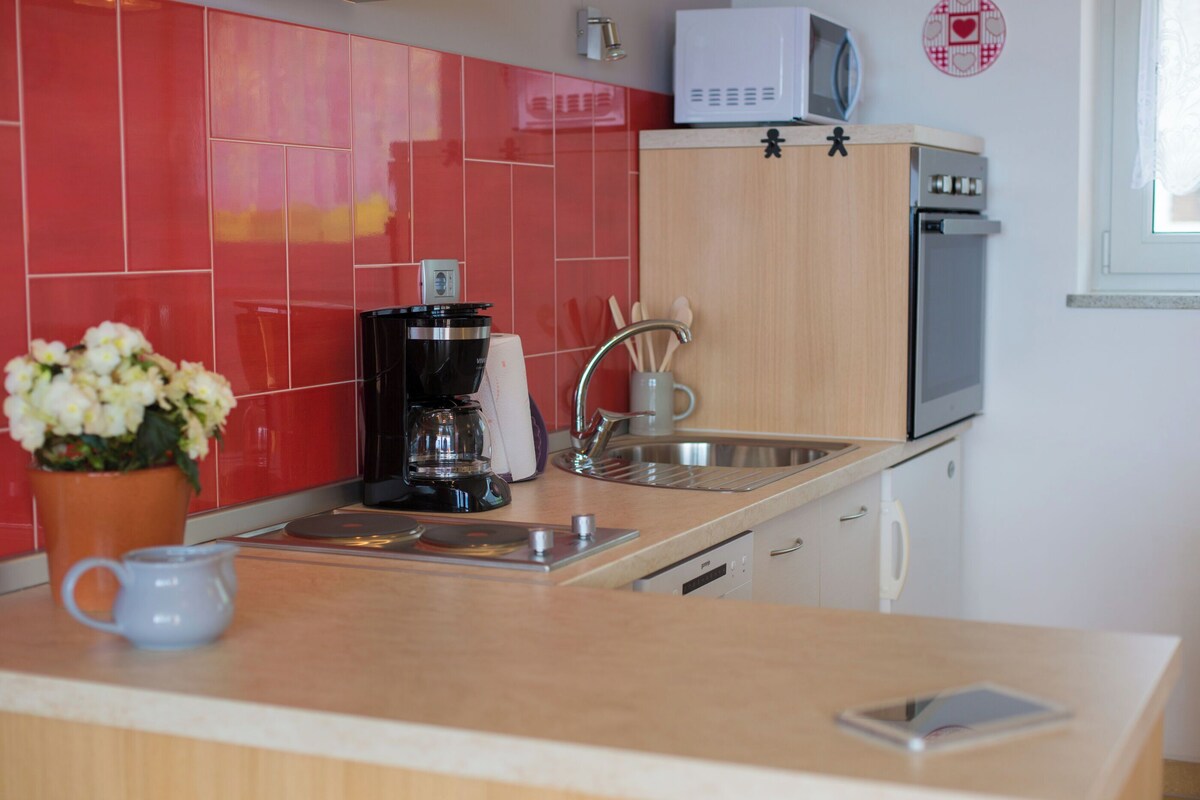 Una cocina con baldosas rojas, cafetera, microondas y lavabo.