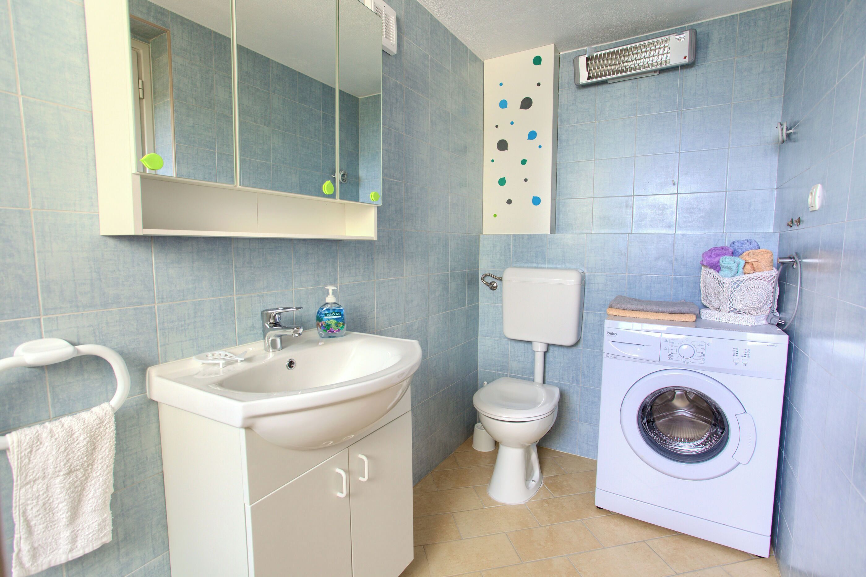 A bathroom with a sink, toilet, and washing machine.