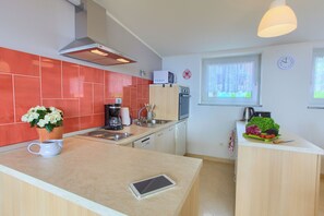 A modern kitchen with a central island, a microwave, a coffee maker, and a sink. - Apartments Rita (Lovran)