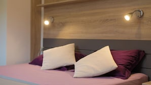 A bed with a wooden headboard, two pillows, and a pink bedspread. - Apartments Rita (Lovran)