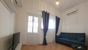 A living room with a TV, a sofa, a coffee table, and a hanging light fixture. - Apartments Boris i Snjezana (Rab)