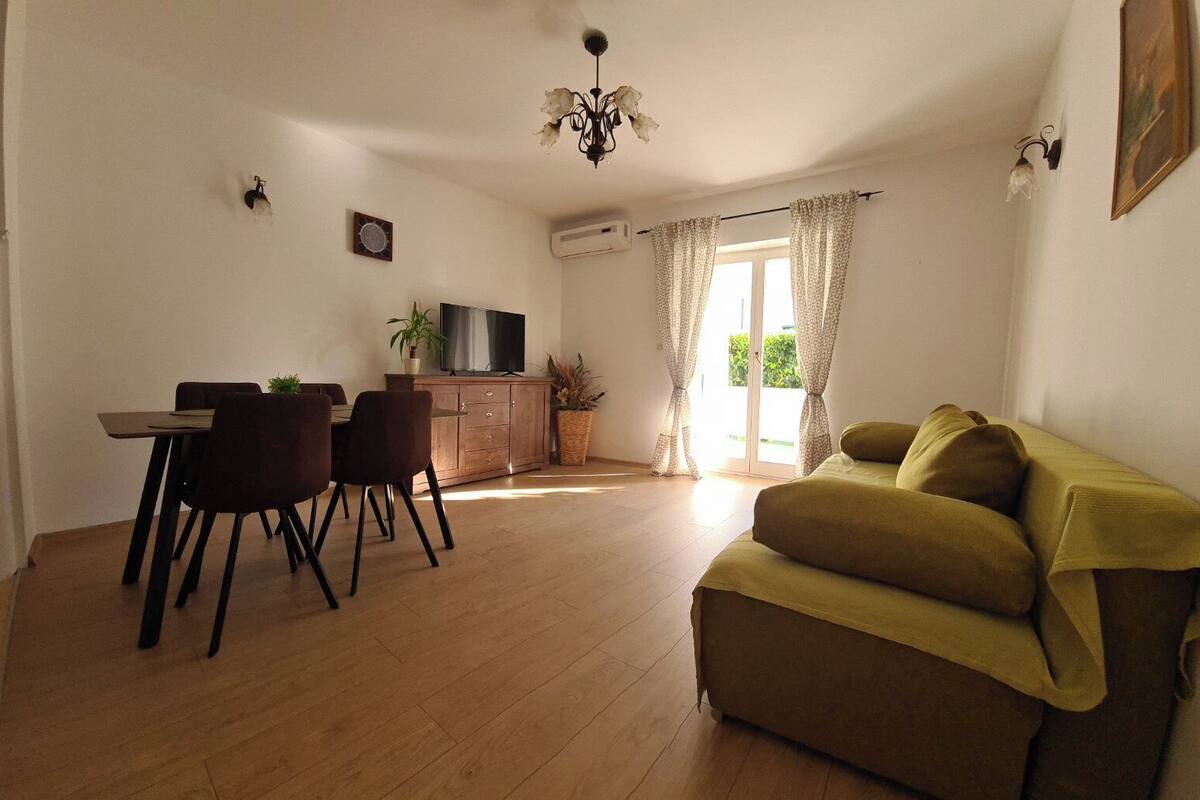 Un soggiorno con divano, un'area pranzo con sedie e tavolo, televisore e una pianta.