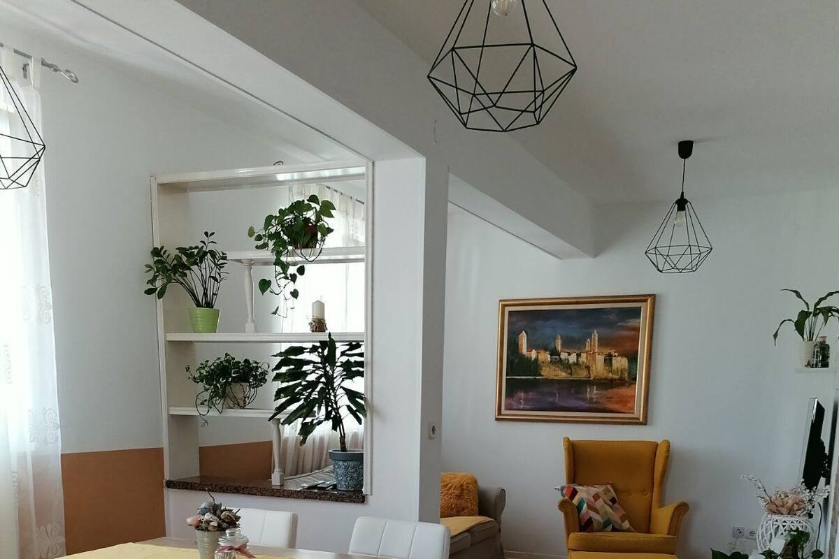 Un soggiorno moderno con zona pranzo, che include una divisa, poltrone, una poltrona gialla, un quadro e piante in vaso.