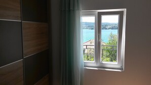 A bathroom with a window overlooking a scenic view of a lake and hills. - Apartments Janja (Solta)