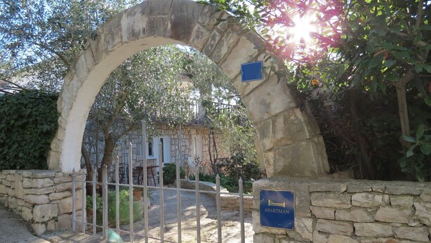 An archway leading to a building with a sign indicating it is an apartment. - Apartments Janja (Solta)