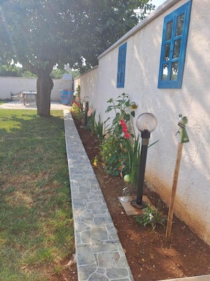 Un'area giardino con un vialetto in pietra, piante in vaso e un lampione.