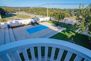 Un cortile residenziale con piscina, poltrona relax e vista sul paesaggio circostante.