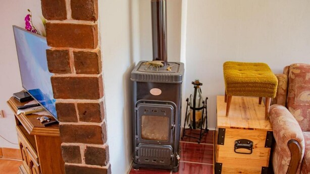 A cozy room with a brick wall, a wood-burning stove, a wooden chest, and a cushioned bench. - House Matan (Tisno)