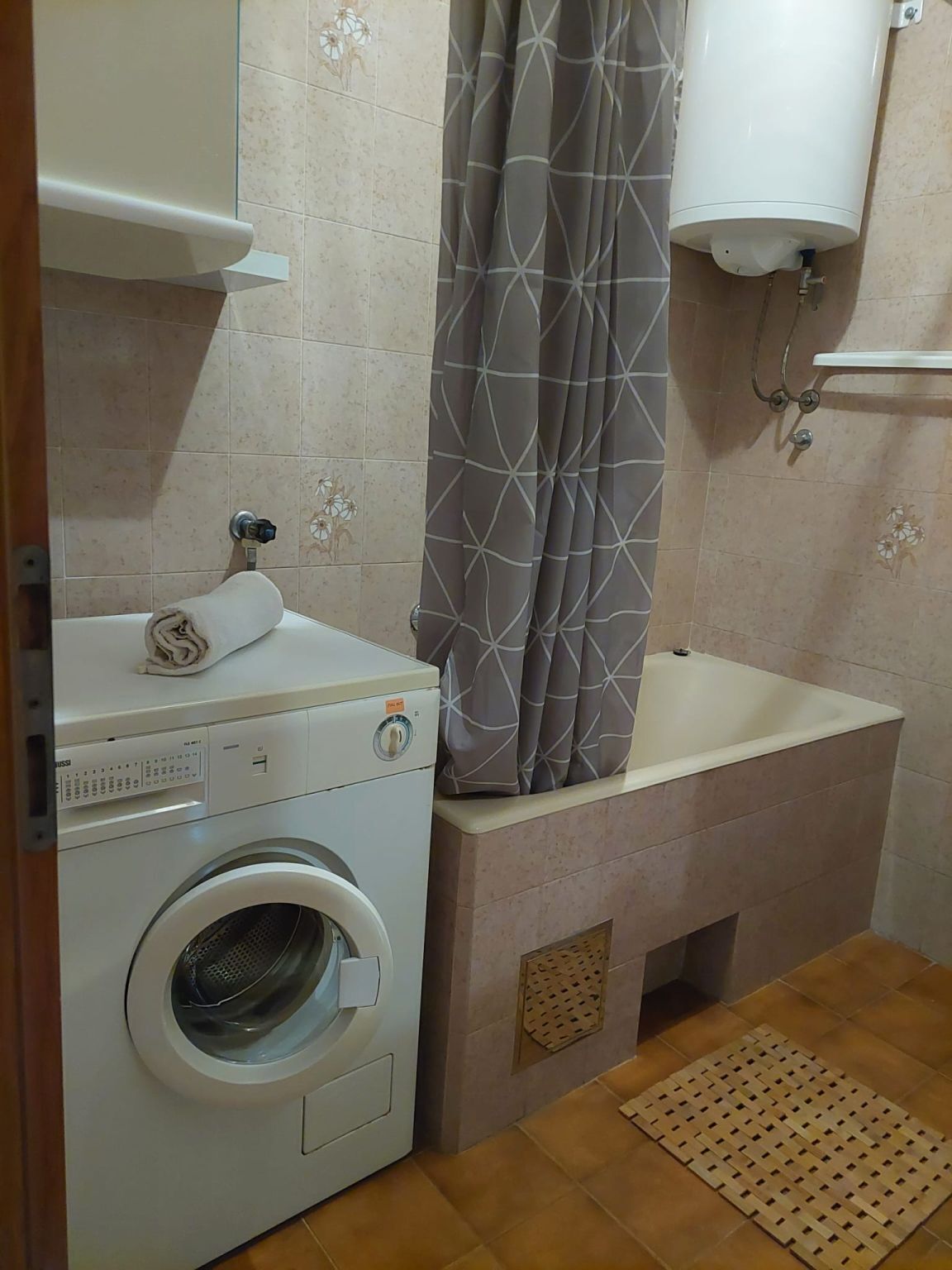 Un baño pequeño con lavadora, lavamanos y cortina de ducha.