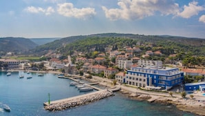 Une ville côtière dotée d’un port de plaisance, de bâtiments et de collines en arrière-plan.