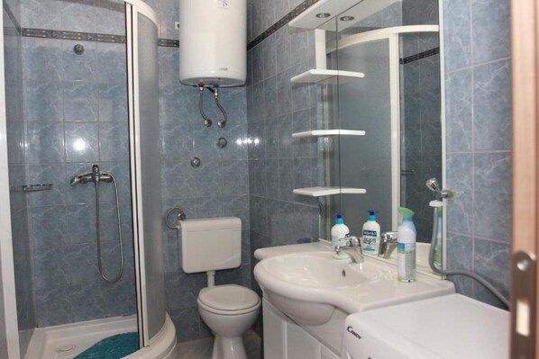 A modern bathroom with a glass-enclosed shower, a toilet, and a sink with a mirror. - Apartment Vinko (Postira)
