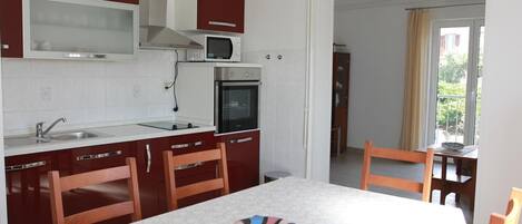 Une cuisine compacte équipée d’un four à micro-ondes, d’un four et d’un évier. Un coin repas avec une table et des chaises est également disponible.