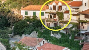 Un quartiere residenziale con edifici in pietra, tetti in tegole rosse e aree verdi.
