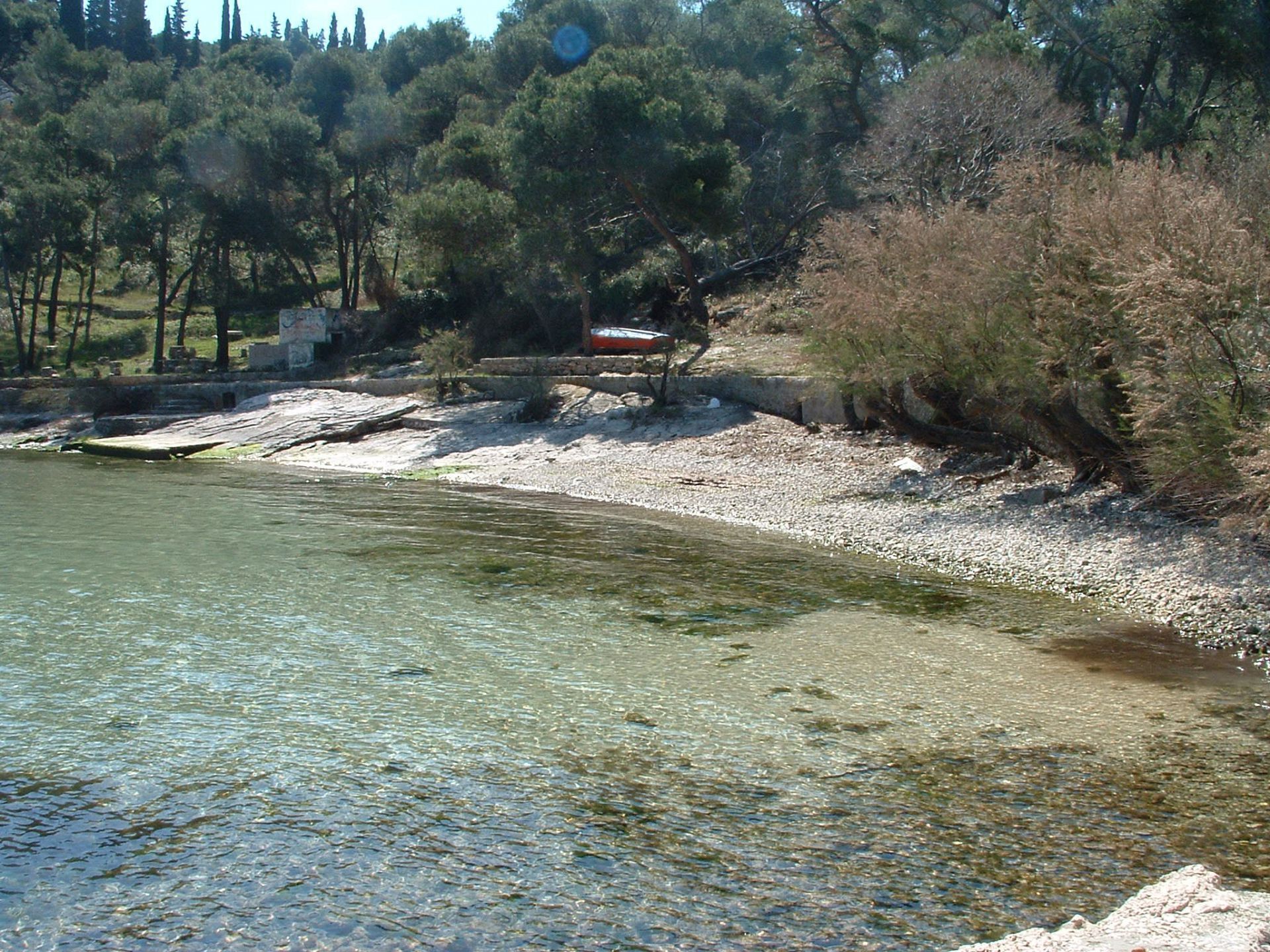 Un lac aux eaux limpides, bordé d’une rive rocheuse et avec des arbres en arrière-plan.