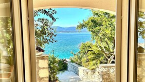 A framed view of a coastal landscape with a clear sky, a stone pathway, and greenery. - Apartments Matea (Bol)