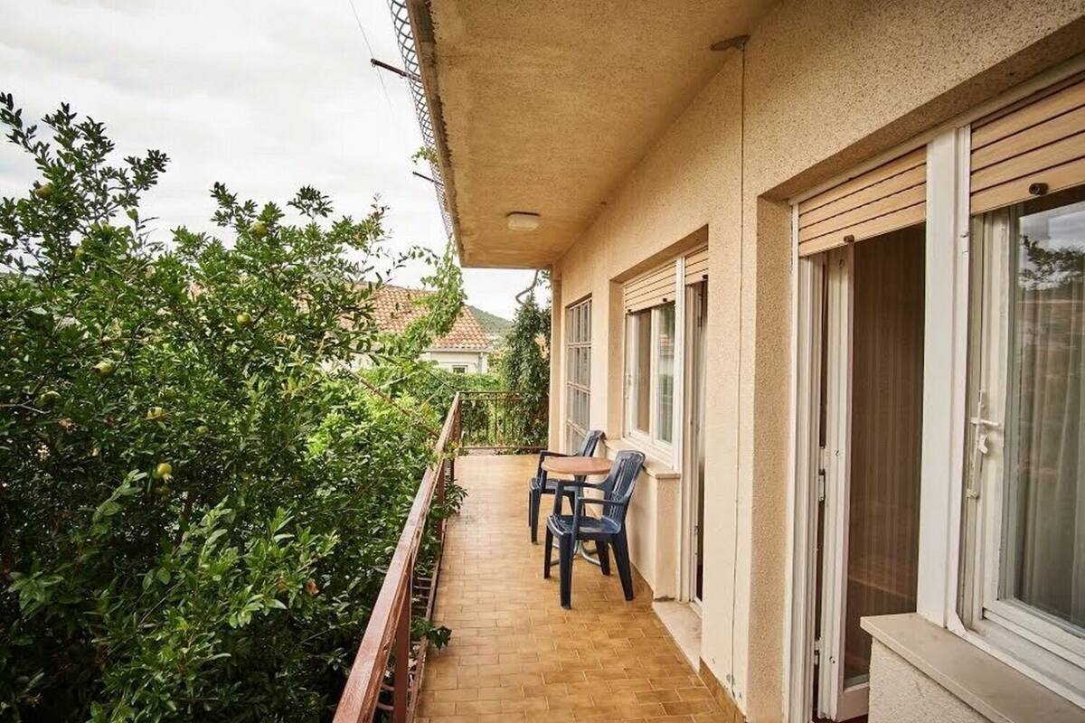 Un balcon avec un plancher en bois, deux chaises et une table.