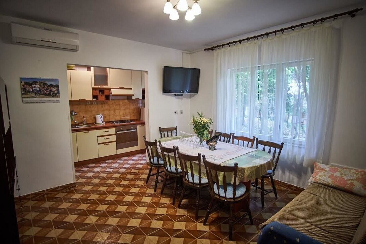 Ein Essbereich mit einem runden Tisch, Stühlen und einem an der Wand montierten Fernseher.