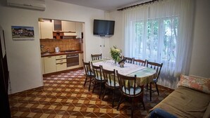 Un comedor con una mesa redonda, sillas y un televisor montado en la pared.