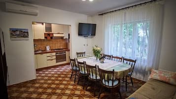 Ein Essbereich mit einem runden Tisch, Stühlen und einem an der Wand montierten Fernseher.