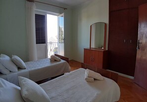 A room with two beds, a wooden wardrobe, a mirror, and a door. - Apartments Mar (Sutivan)