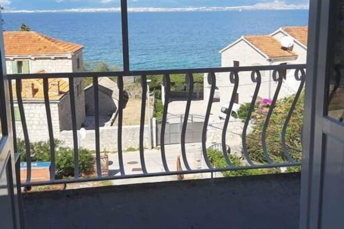 A balcony with a metal railing overlooking a coastal view.