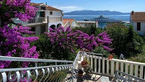 A staircase leading to a balcony with a view of a coastal town, including a ship named "L. A. C. A. DELFINA" in the distance. - Apartments Nada (Sucuraj)
